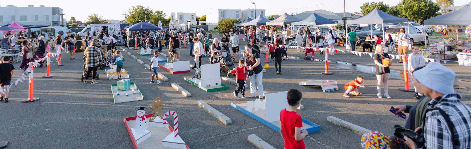 A large crowd of people excitedly fill the open church block outside, which has been set up with market and food stalls along with Christmas games and activities.