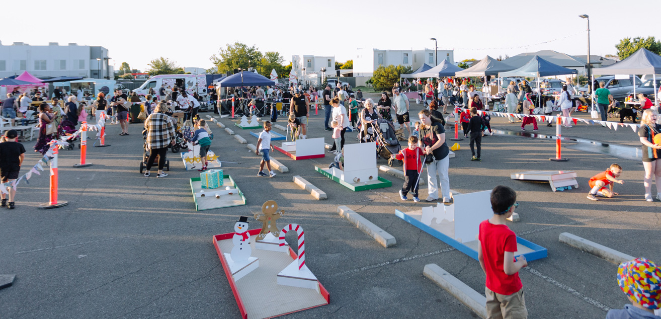 A large crowd of people excitedly fill the open church block outside, which has been set up with market and food stalls along with Christmas games and activities.
