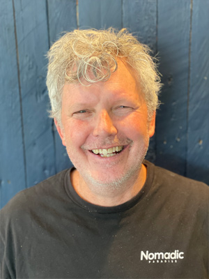 Pete Riggs, is smiling a big smile, his teeth showing.