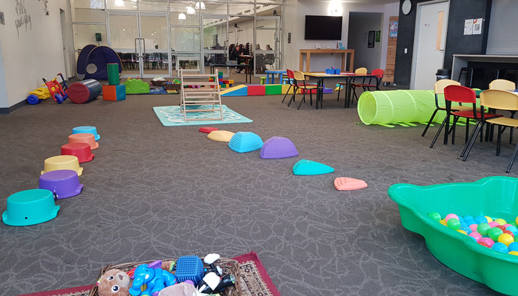 The church foyer is filled with children's toys and activities in preparedness for playgroup to being. There is tricycles, ball pit, stepping stones, a tunnel and slide along with tables filled with craft and colouring ready for the children to enjoy.